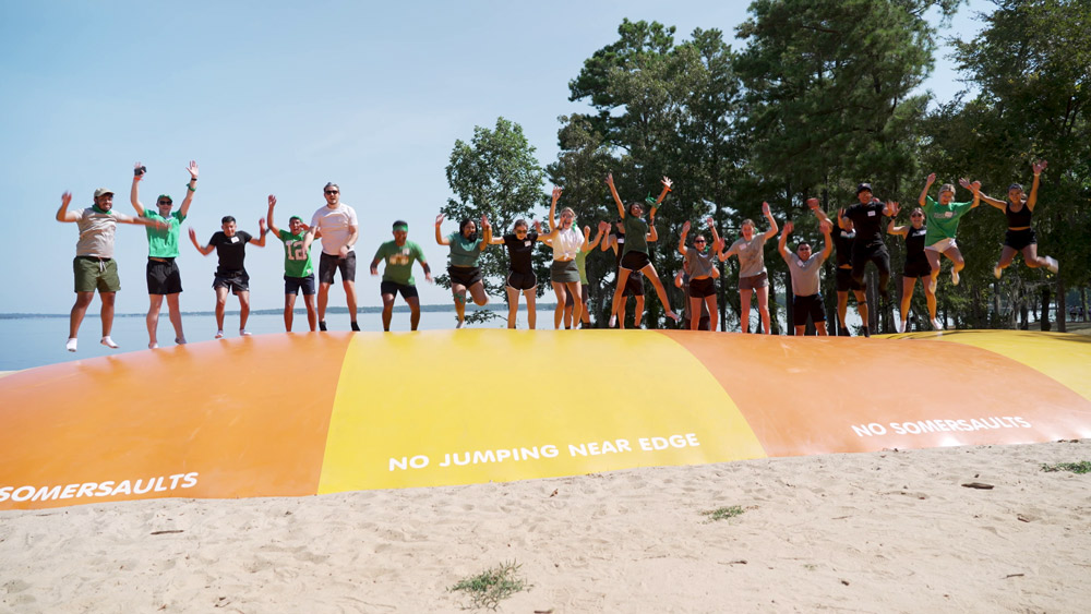 McGovern Medical School students jump for joy on a red and yellow inflatable at the Henry Strobel Retreat.