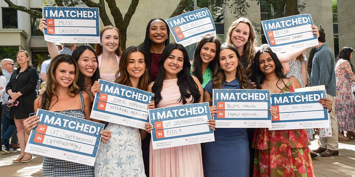 Group of medical students pose outdoors during Match Day celebration at McGovern Medical School, holding “I Matched!” signs announcing residency placements and specialties including urology, internal medicine, pediatrics, family medicine, ophthalmology, ENT, and orthopedic surgery.