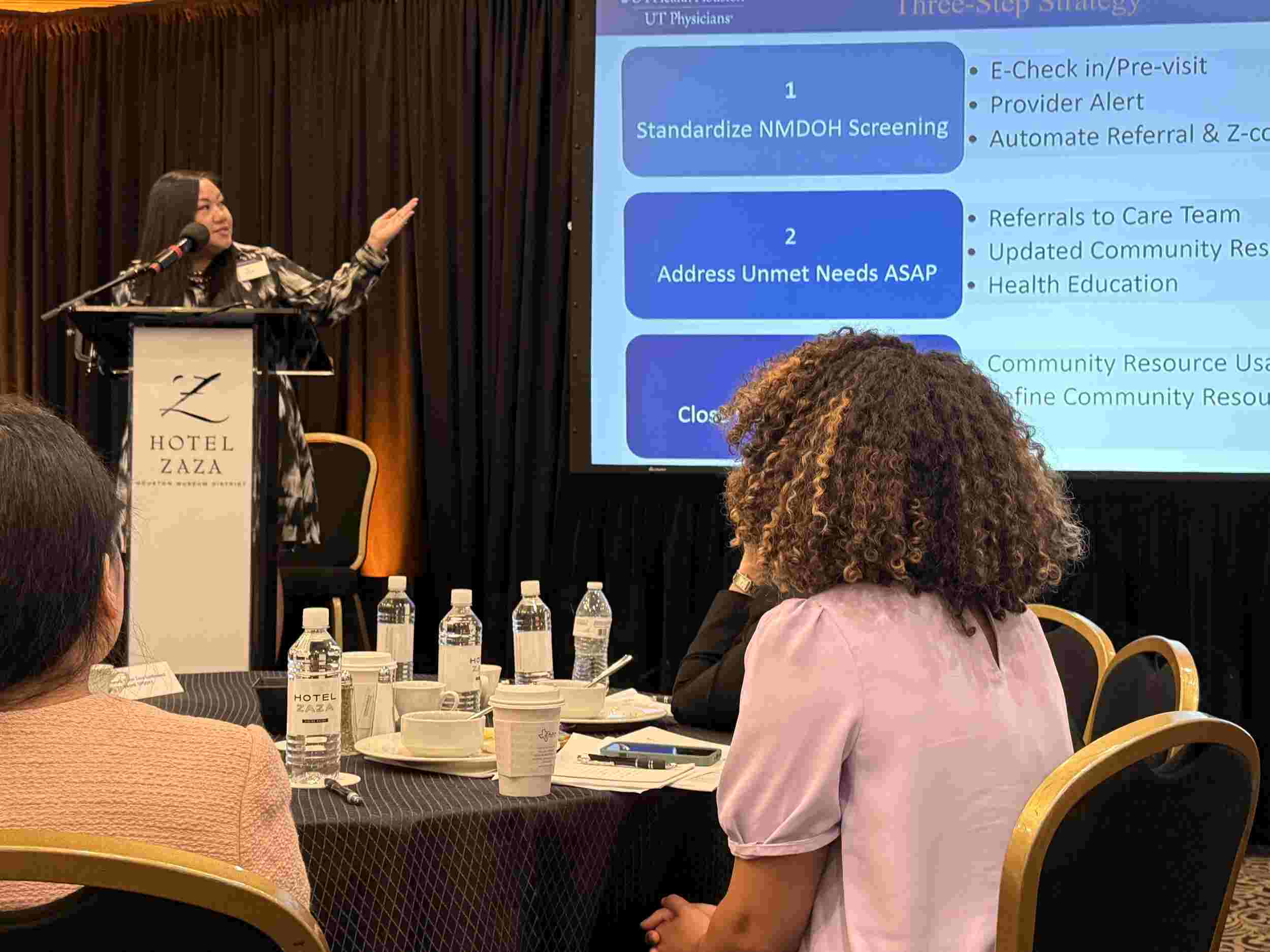 Healthcare presenter sharing slides on unmet needs and closed loop referrals.
