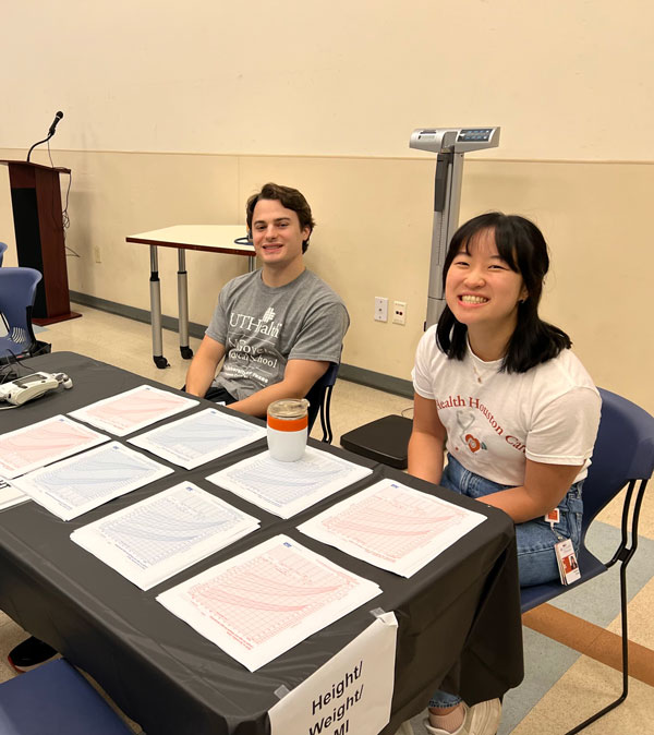 student volunteers manning information table at the health fair