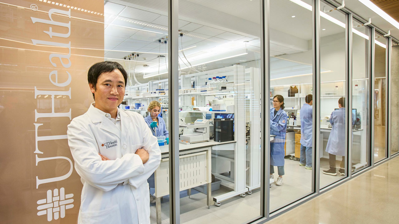 Photo of Kyoji Tsuchikama, PhD, standing in front of a lab wearing a white coat and folding his arms. (Photo by UTHealth Houston)