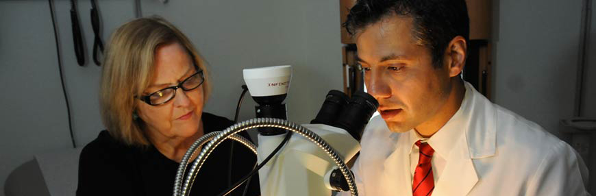 Dr. Assassi looking through a microscope