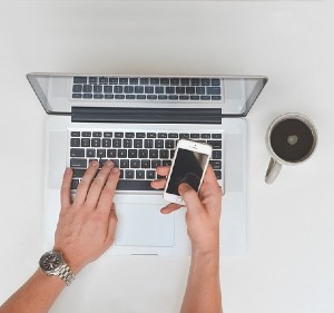 hands using a laptop and a mobile telephone