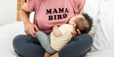 woman breastfeeding infant in shirt that says mama bird