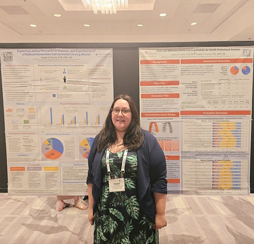 Angela Gomez stands in front of two poster presentations