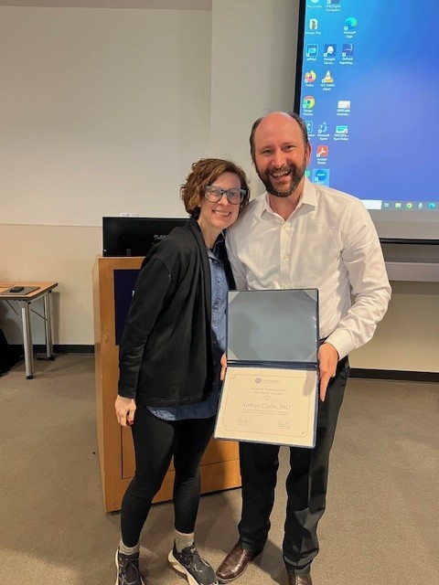 Nathan Carlin holds certificate standing next to Claire Clark