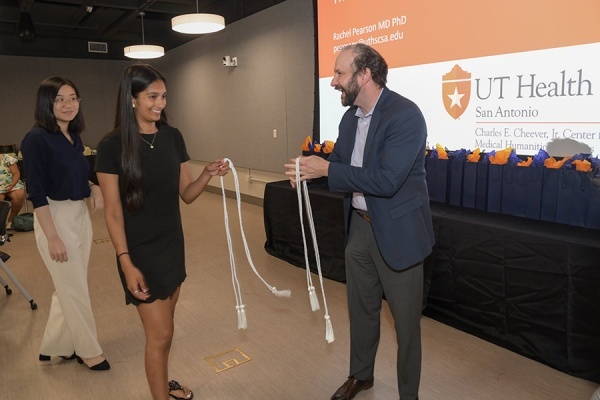 Students receive white honor cords from Nathan Carlin