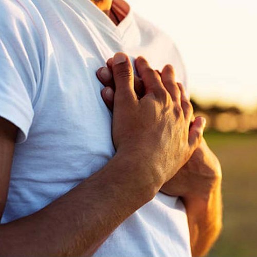Person in white t-shirt with hands clasped over chest