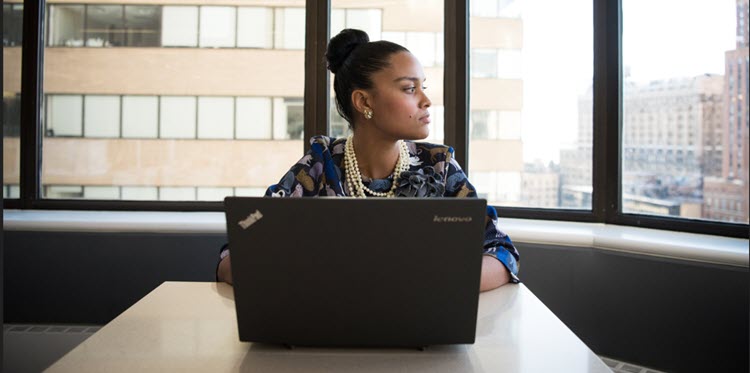 Woman of color wearing a bun sitting at laptop