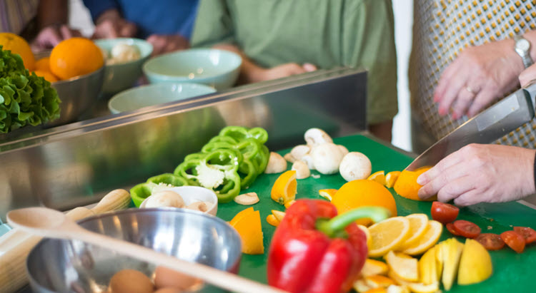 Fresh vegetables being sliced on a cutting board during a group medical nutrition therapy session, illustrating hands‑on dietary education.