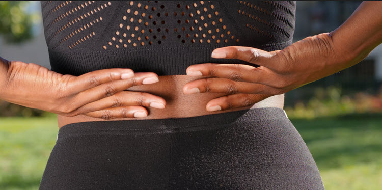 person in black sports wear grabbing lower back