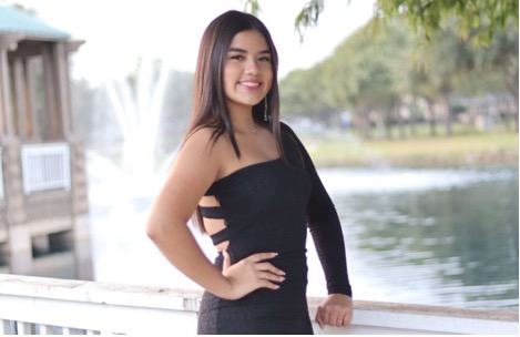Photo of Sara Paez modeling a black dress in front of a lake.