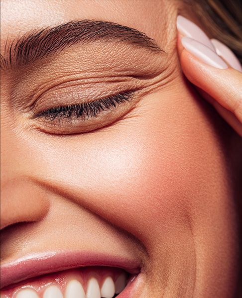 close up of a woman's eye with her fingers touching the side of her head