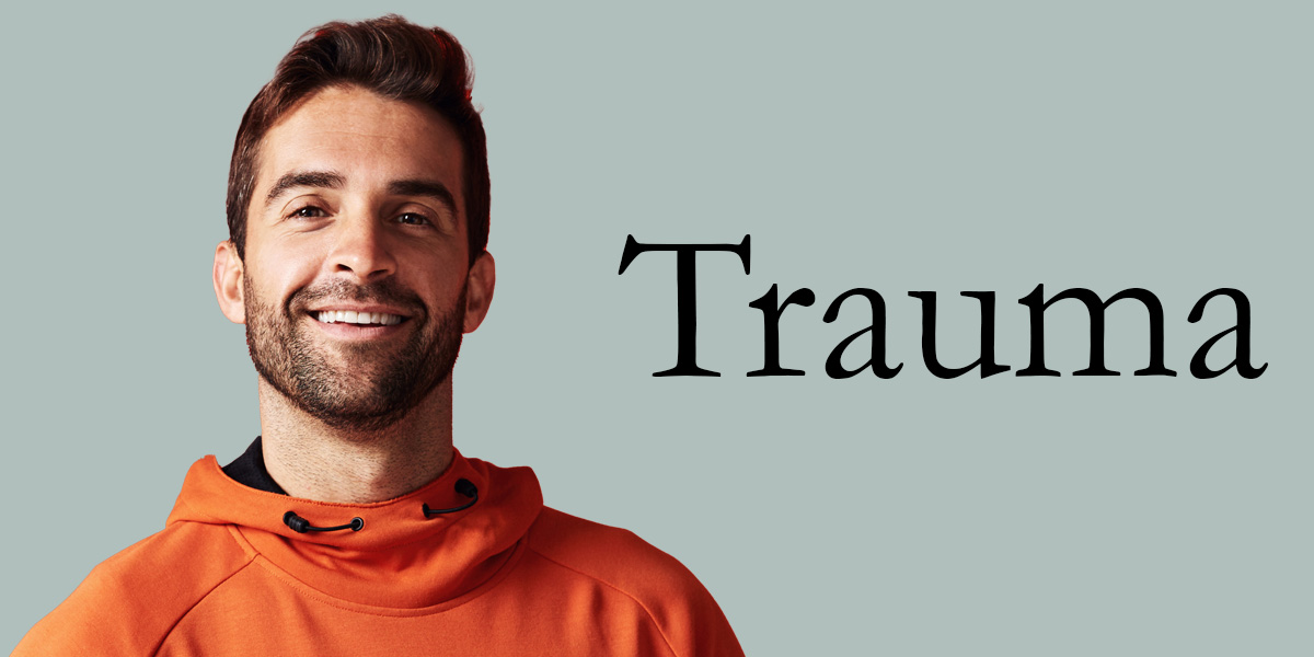 white man with beard wearing an orange hoodie next to the word trauma