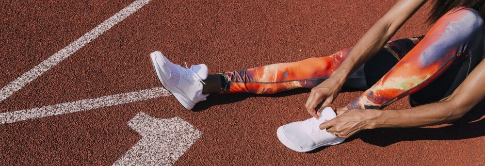 athlete on running tracks tying shoe