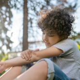 Young child holding their elbow in pain, consistent with nursemaid’s elbow