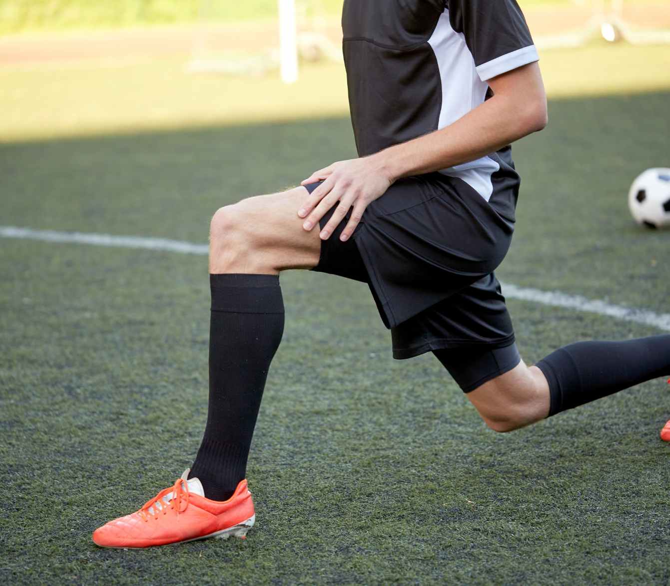 Soccer player experiencing groin pain while warming up on the field.