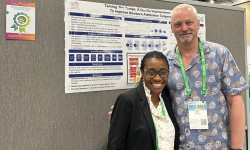 Two doctors standing in front of research poster