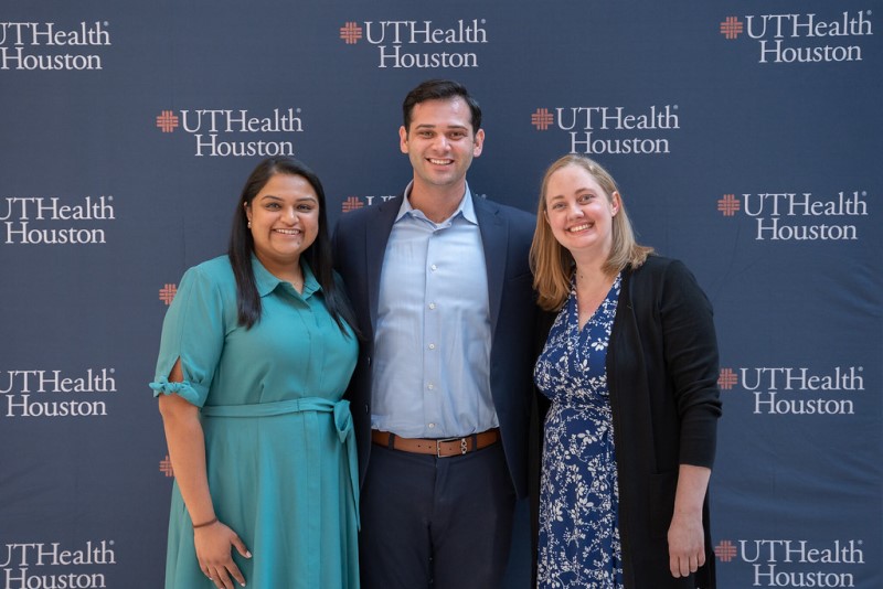 Three health professionals standing in front of UTHealth Houston banner