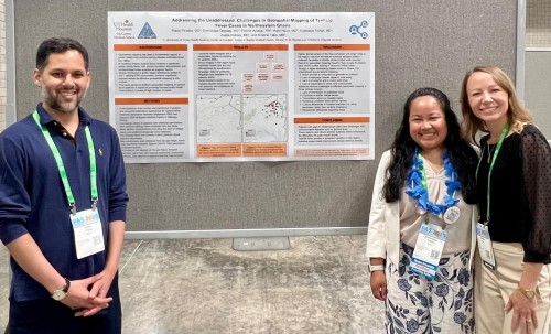 Three doctors standing in front of research poster