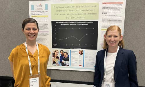 Two clinicians in front of research poster