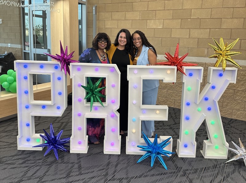 Three women posing behind "PRE-K" sign