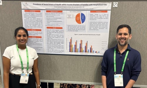 Two doctors standing in front of research poster