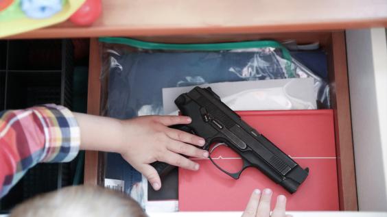 small child reaching for a gun in drawer