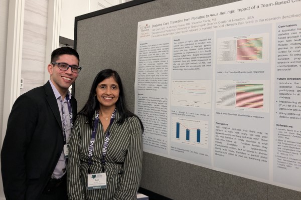 Two doctors standing in front of research poster