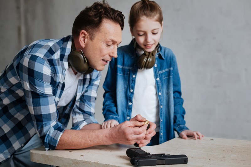 Man and child examine bullet and gun