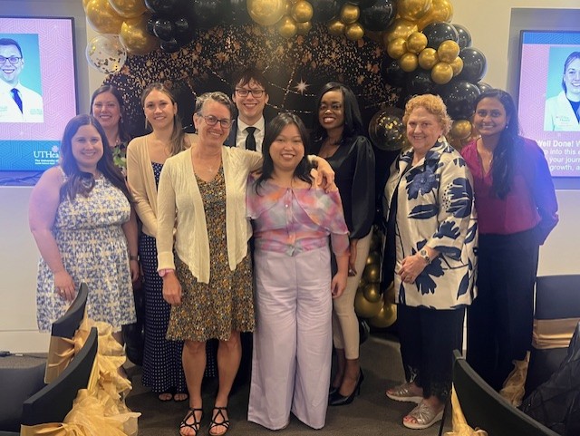 Group of people in front of black and gold balloon arch