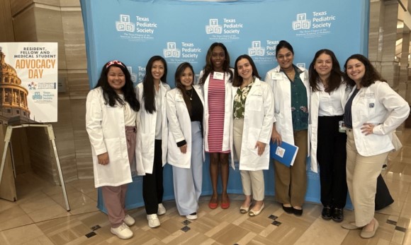 Doctors in whitecoats in front of banner