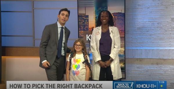 News anchor, doctor, and little girl smile at camera
