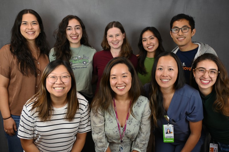 Group of smiling people posing in front of backdrop