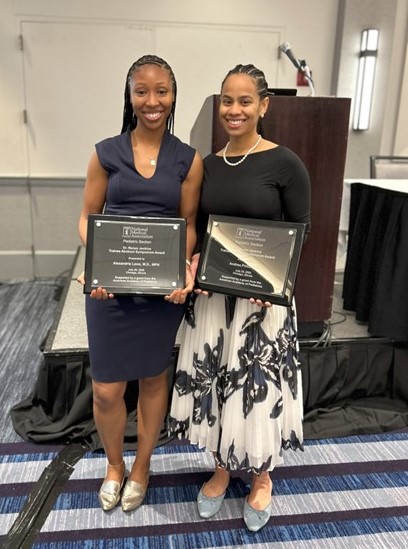 Two women holding award plaques
