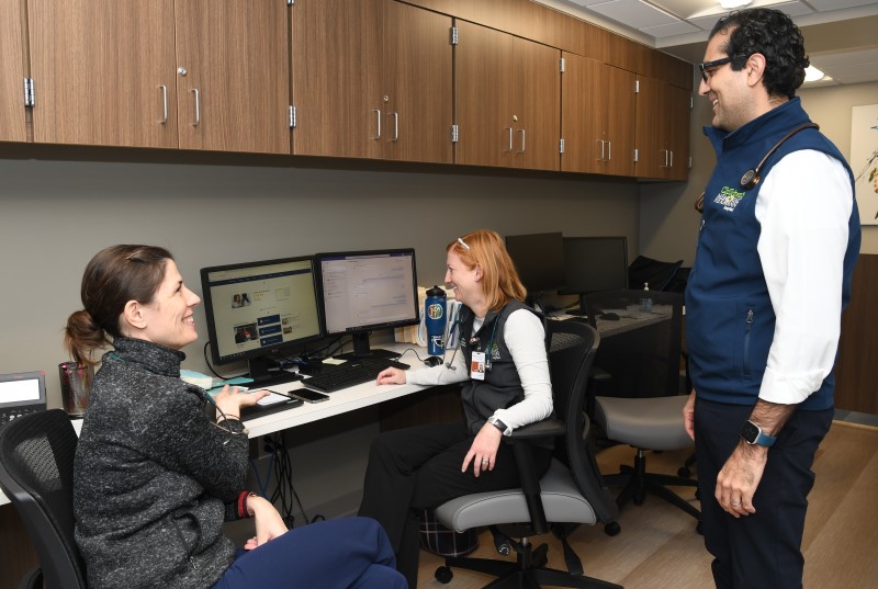 Three people talking and looking at a computer