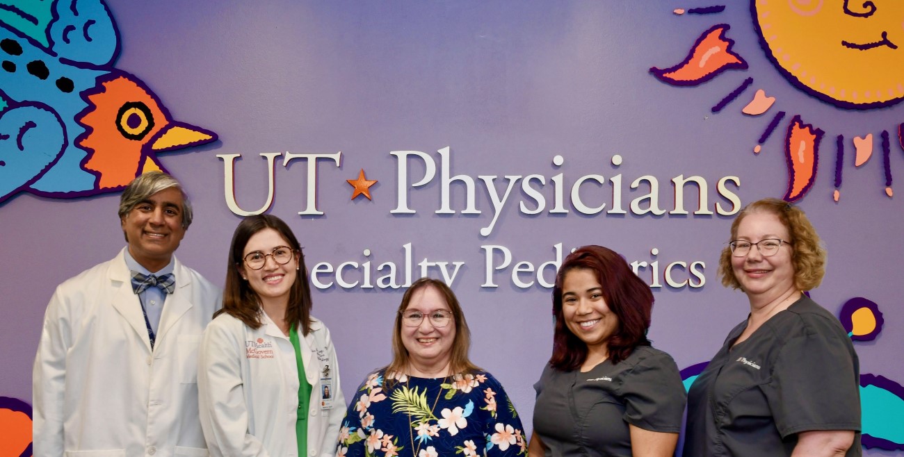 Doctors and medical assistants in front of colorful clinic backdrop