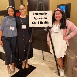 Three doctors standing next to a sign on an easel