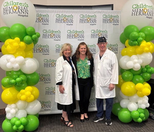 Three people smiling in front of banner