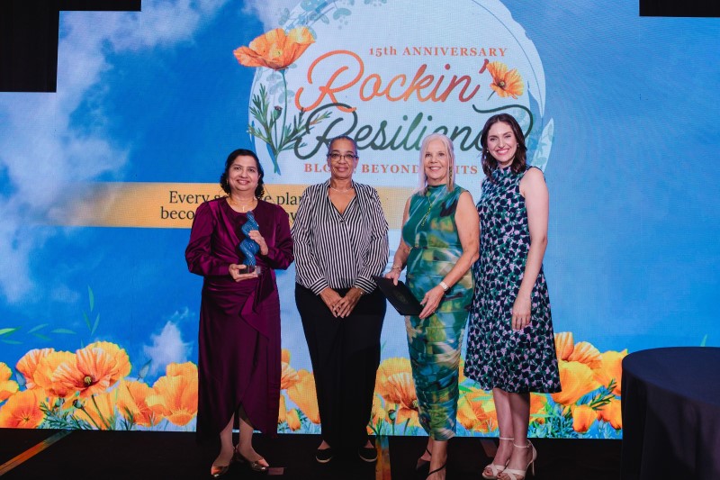 Four women in front of screen at award ceremony