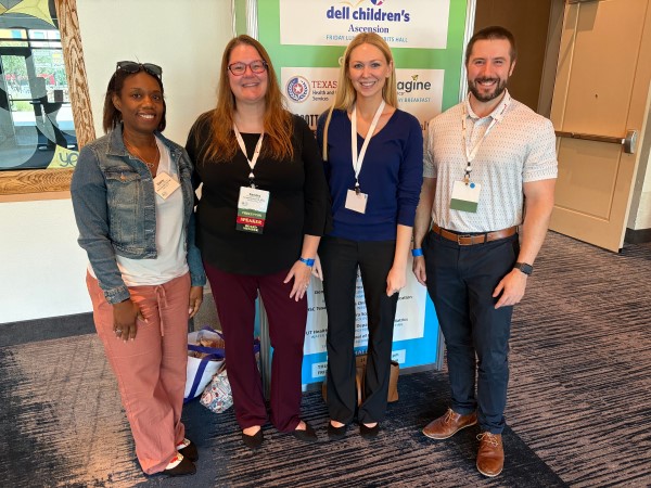 Four people standing in front of research posters