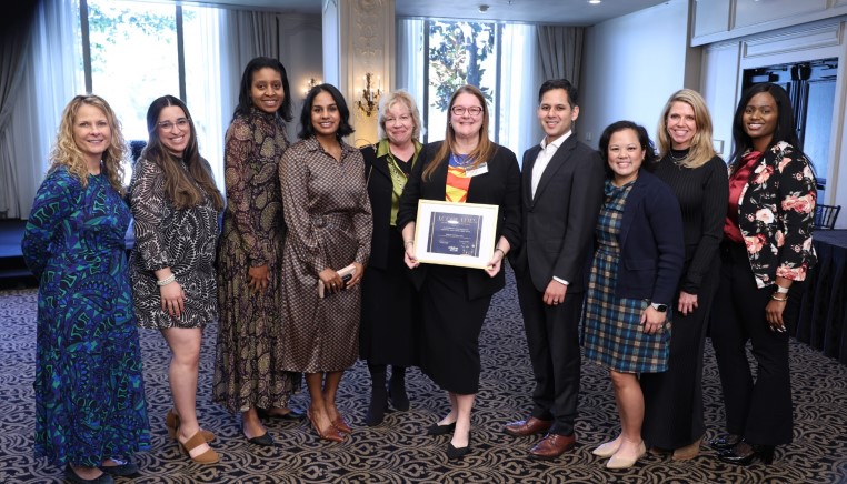 Group gathered around woman holding award
