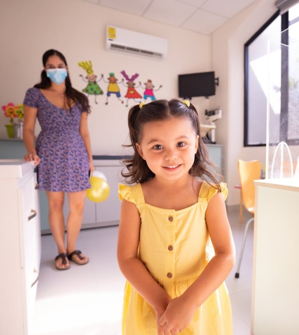 Little girl in yellow dress smiling in exam room
