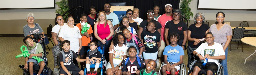 Group of adults and children in front of black curtains