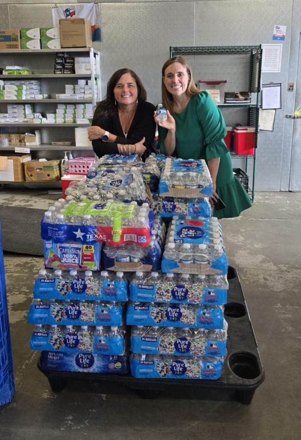 Two women standing behind cart full of bottled water