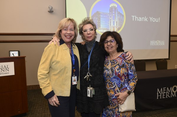 Three doctors posing for camera in front of powerpoint screen