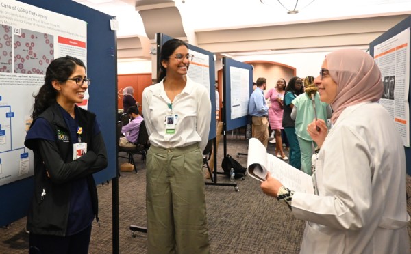 Three women discuss a research poster