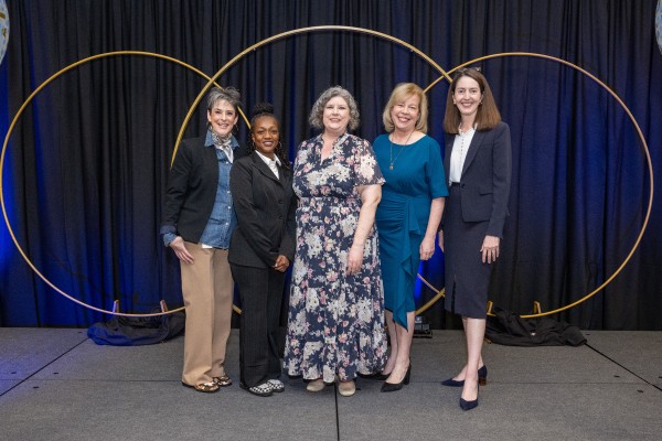 Five well-dressed women on a stage