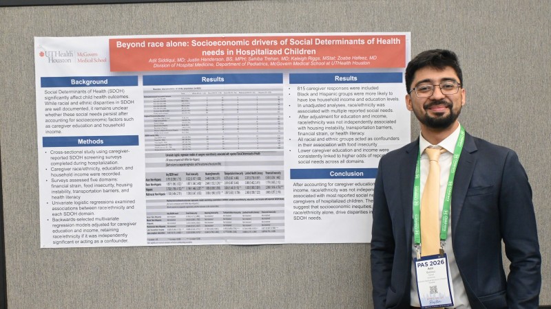 Dr. Siddiqui stands in front of research poster