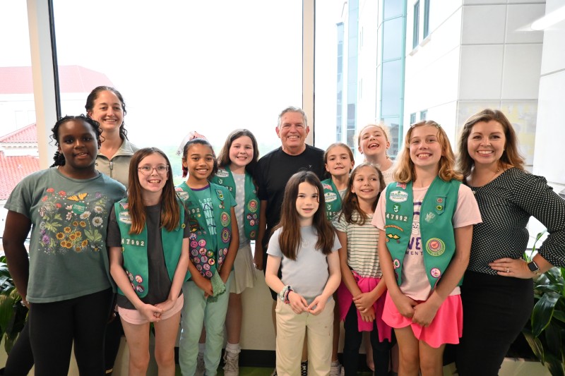 Group of Girls Scouts and adult leaders in front of window
